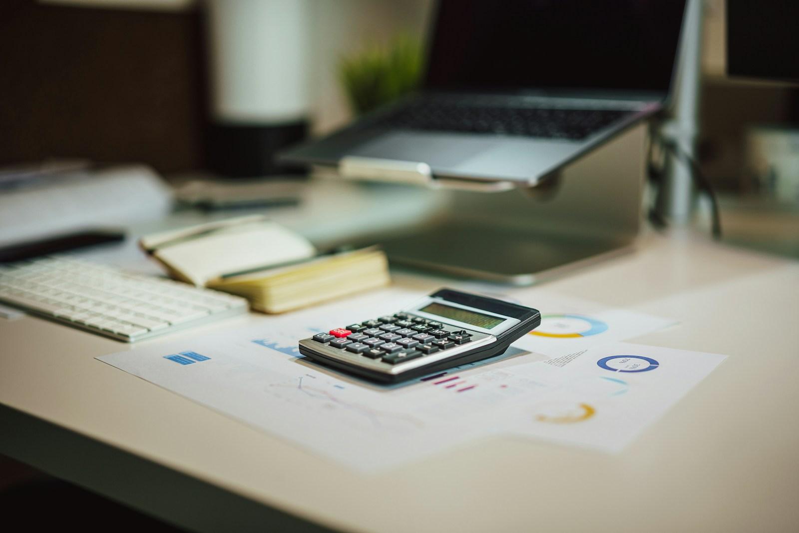 Calculadora e anotações sobre uma mesa de trabalho
